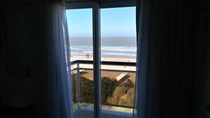 Uitzicht vanaf een balkon op een strand, met een heldere lucht.