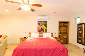 A bedroom with a bed, a ceiling fan, a bookshelf, and an air conditioning unit. - Lawson Rock Yellowfish 110 (Roatan)
