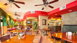 Un restaurante con varias mesas y sillas, ventiladores de techo y una zona de bar.
