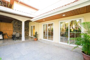 A covered patio area with a stone wall, a wooden ceiling, and a large window. - Lawson Rock Yellowfish 110 (Roatan)