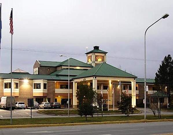 A hotel with a central tower, a covered entrance, and a parking lot with several cars. - Hotel Land Express Neuquén (Neuquén)