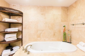 Une salle de bain avec une baignoire, des étagères avec des serviettes pliées et un espace douche.