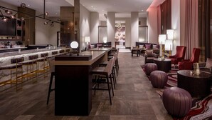 Un moderno vestíbulo de hotel con área de bar, asientos y un espejo grande.