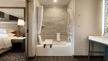 Un baño moderno con bañera, ducha y una pequeña mesa.