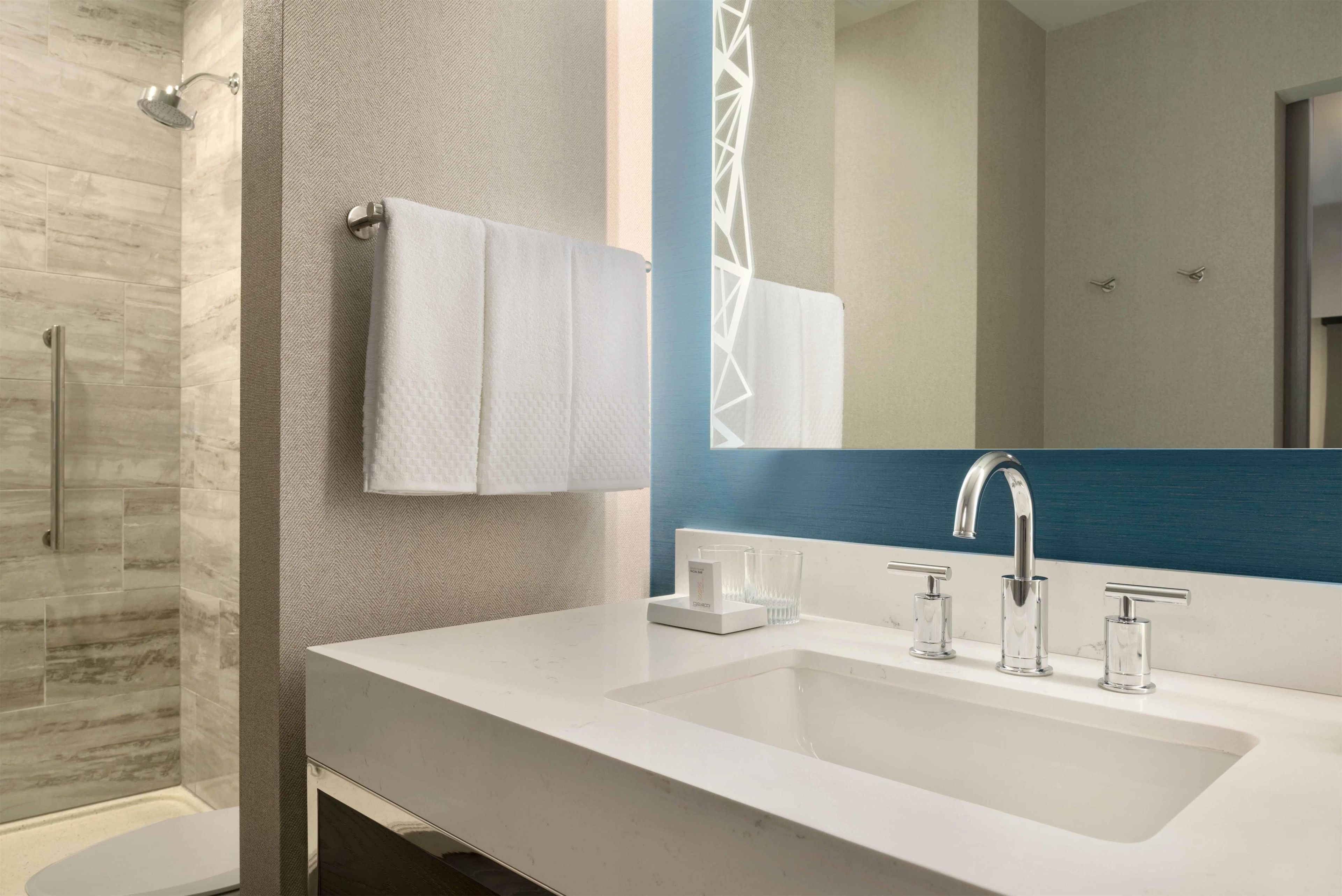 A modern bathroom with a white sink, a mirror, and a shower.