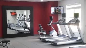 Een sportschool met loopbanden, een hometrainer en een roeiapparaat.