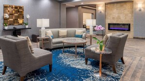 Una sala de estar moderna con un sofá gris, dos sillones, una mesa de centro y una chimenea.