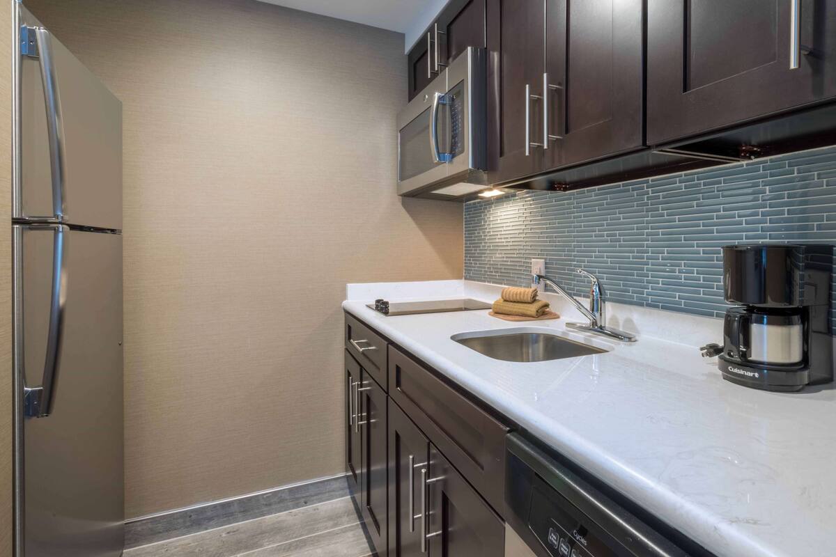 A modern kitchen with stainless steel appliances, a double sink, and a coffee maker.