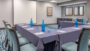 A conference room with a long table, blue chairs, and water bottles.