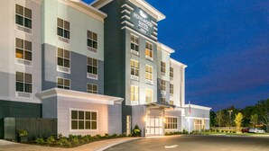 Un hotel de varios pisos con fachada moderna, ventanas grandes y una entrada con galería techada.