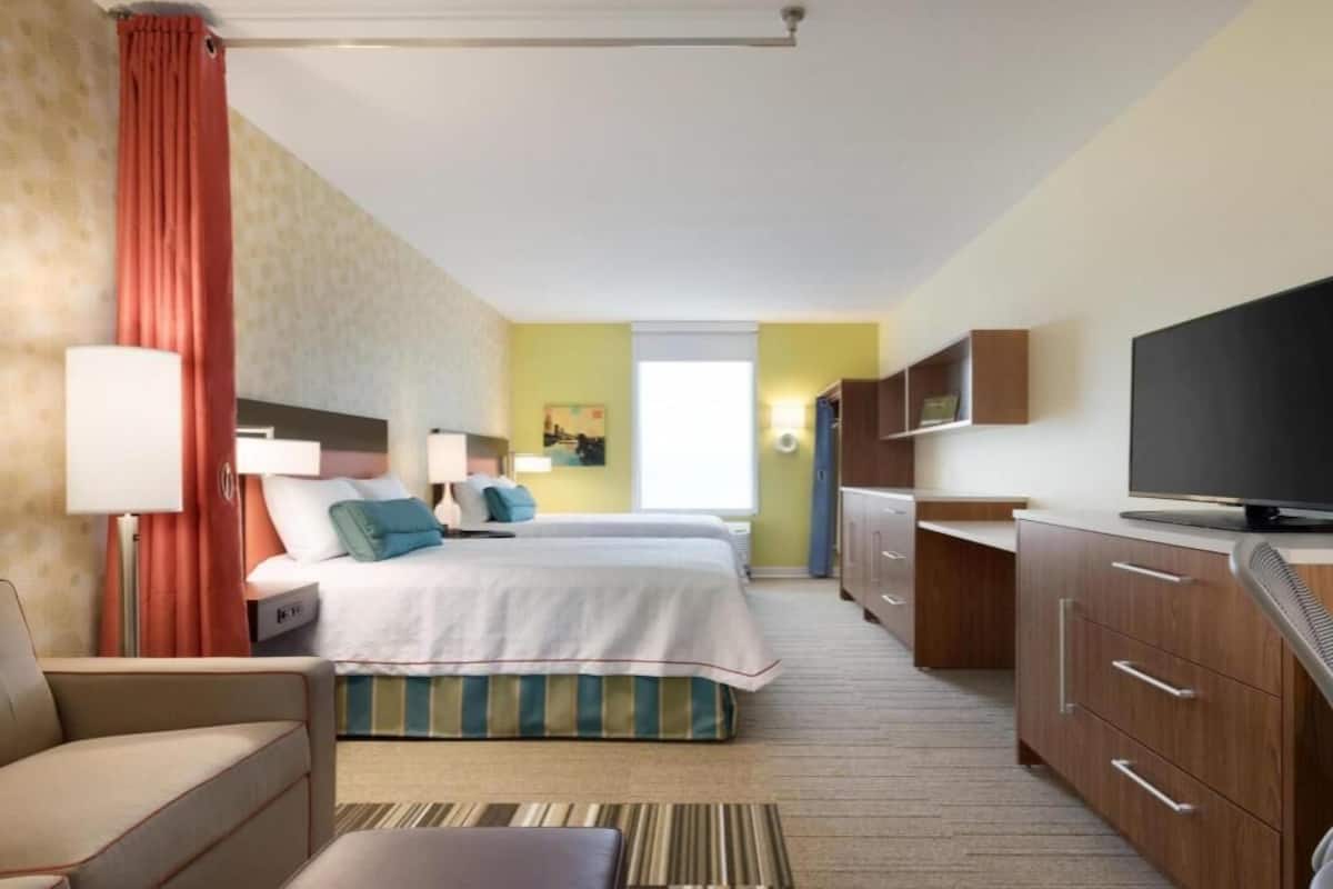 A hotel room with a bed, a desk, a TV, a sofa, and a bathroom.
