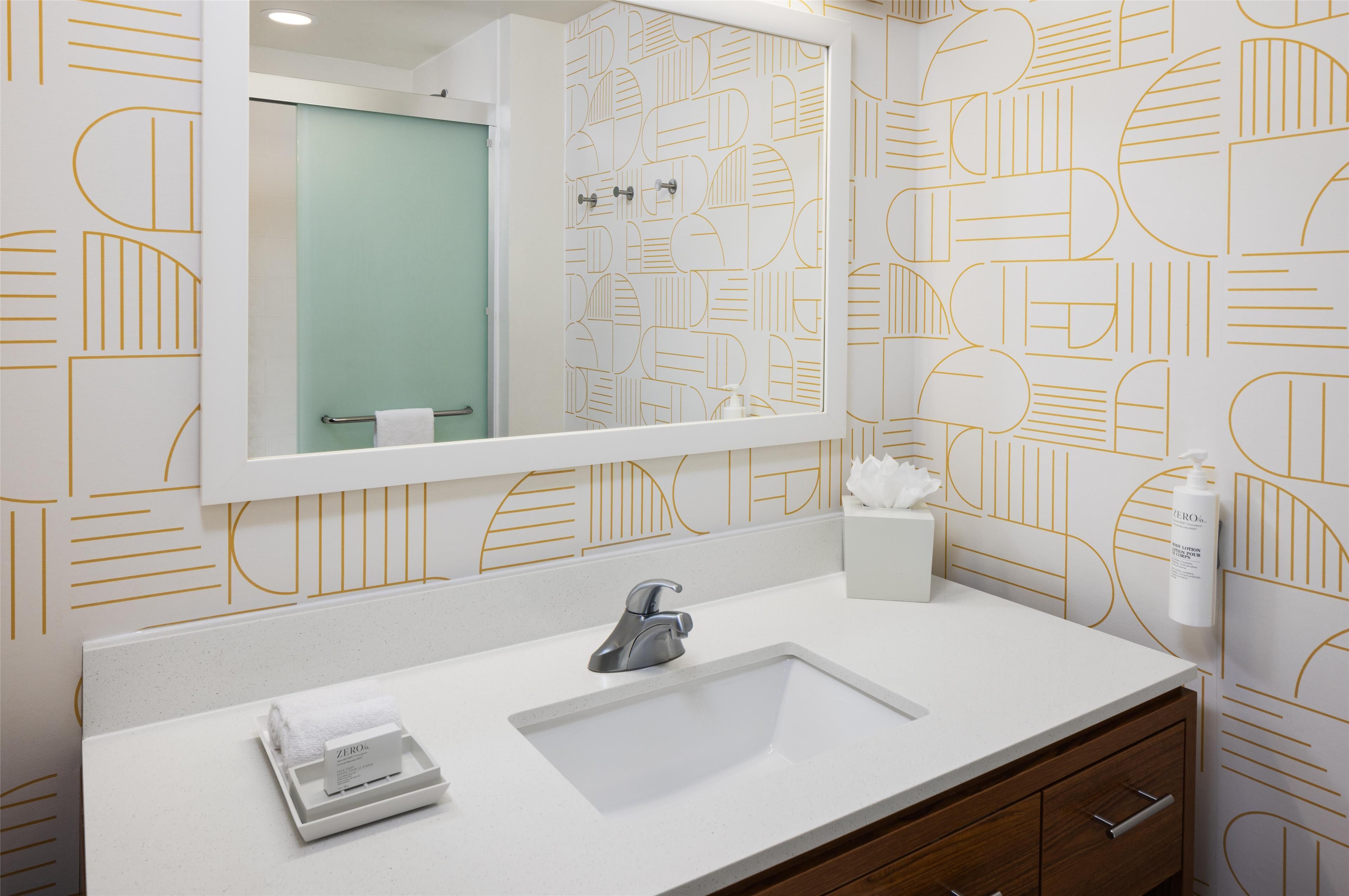 A bathroom with a white sink, a mirror, and a towel rack.