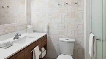 A bathroom with a white sink, mirror, and toilet.