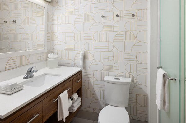 Baño con lavamanos, espejo y retrete blancos.