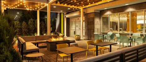 Un espacio al aire libre con patio, mobiliario, mesas y una chimenea.