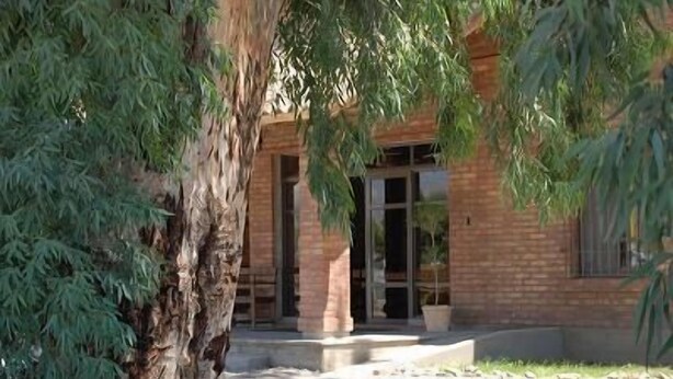 A building with a brick facade, a glass door entrance, and a concrete pathway leading to the door. - Aire Andino Apart Hotel (San Juan)