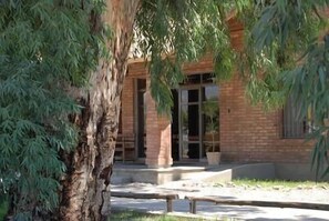 Un bâtiment à la façade en briques, doté d’une porte d’entrée en verre et d’un chemin en béton menant à la porte.