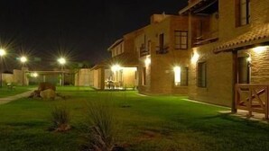 A building with multiple rooms, a covered outdoor area, and a well-lit lawn at night. - Aire Andino Apart Hotel (San Juan)