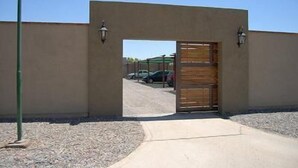 A gated entrance to a building with a clear view of parked cars in the background. - Aire Andino Apart Hotel (San Juan)