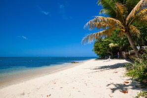 A beach with clear blue water, white sand, and palm trees.