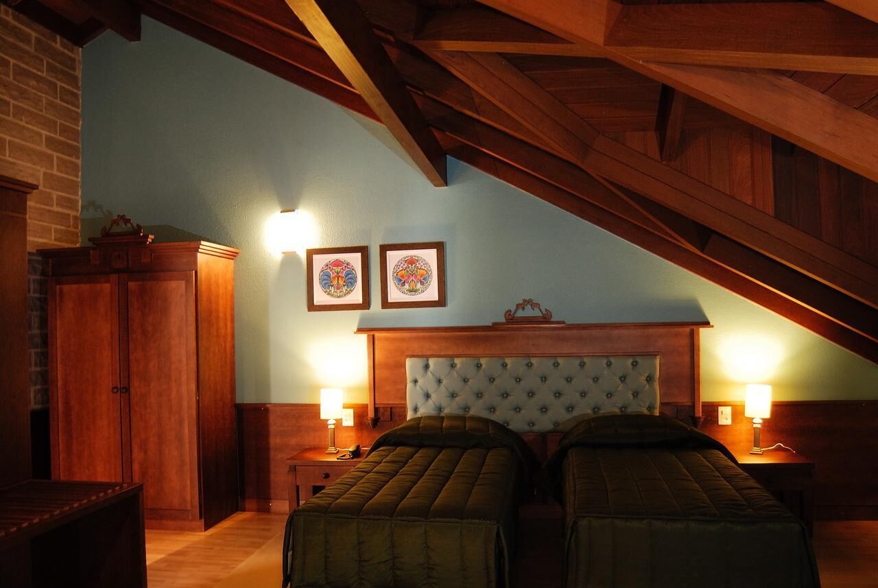 A room with two beds, wooden headboard, two wall-mounted lamps, and a wooden cabinet.