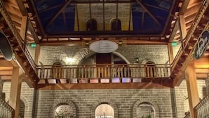 A spacious atrium with a high ceiling, stone walls, and a central staircase. - Pousada Castello Benvenutti (Garibaldi)