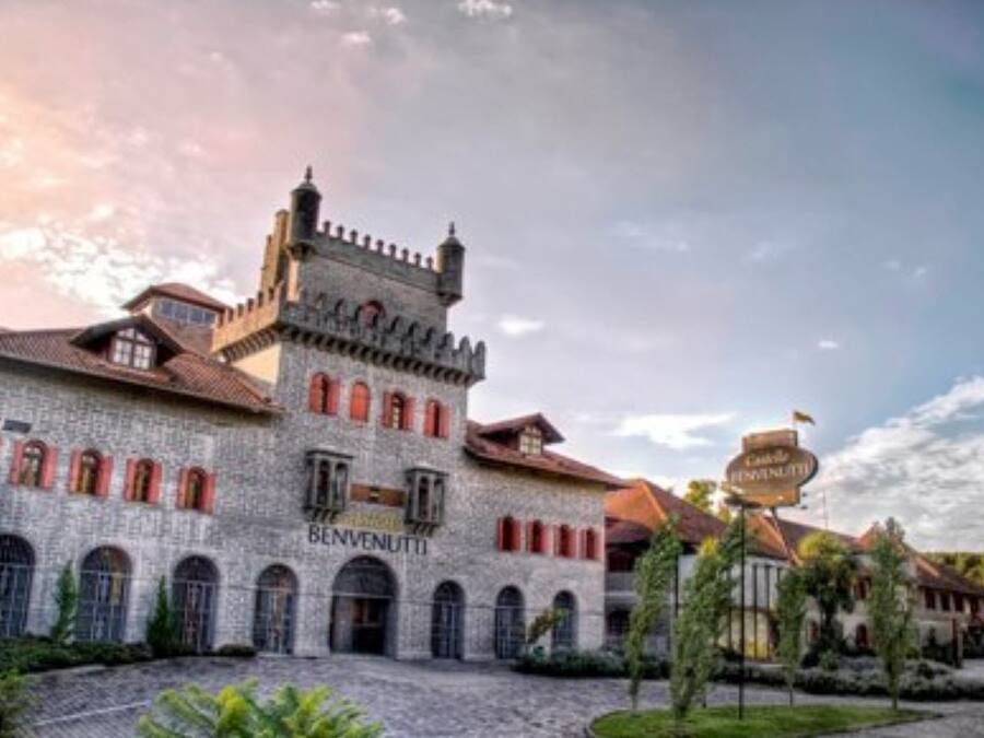 A historic building with a stone facade, arched windows, and a tower. The name "BENVENUTTI" is visible on the building.