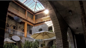 An indoor courtyard with stone walls, wooden balconies, and outdoor seating with umbrellas. - Pousada Castello Benvenutti (Garibaldi)