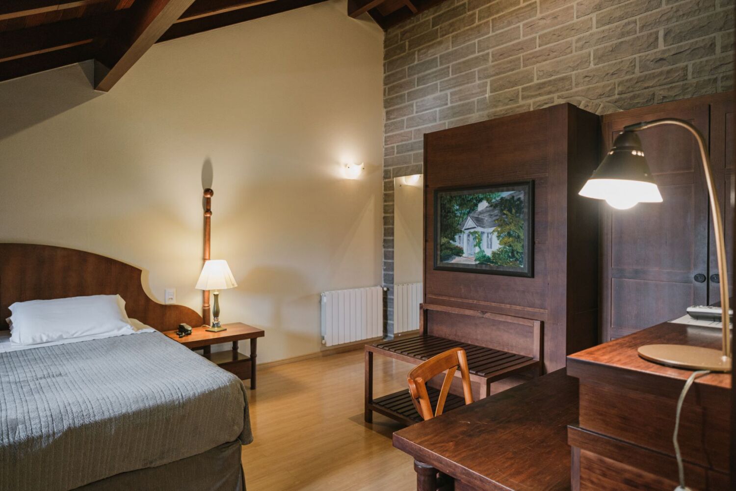 Une pièce confortable avec un lit, un bureau, une chaise, une lampe et une cheminée.