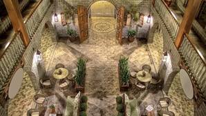 A spacious indoor area with a central open space surrounded by seating arrangements and potted plants. - Pousada Castello Benvenutti (Garibaldi)
