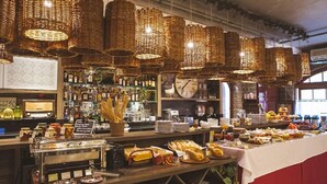 A buffet area with wicker chandeliers, a bar with liquor bottles, and a variety of food and drink options. - Pousada Castello Benvenutti (Garibaldi)
