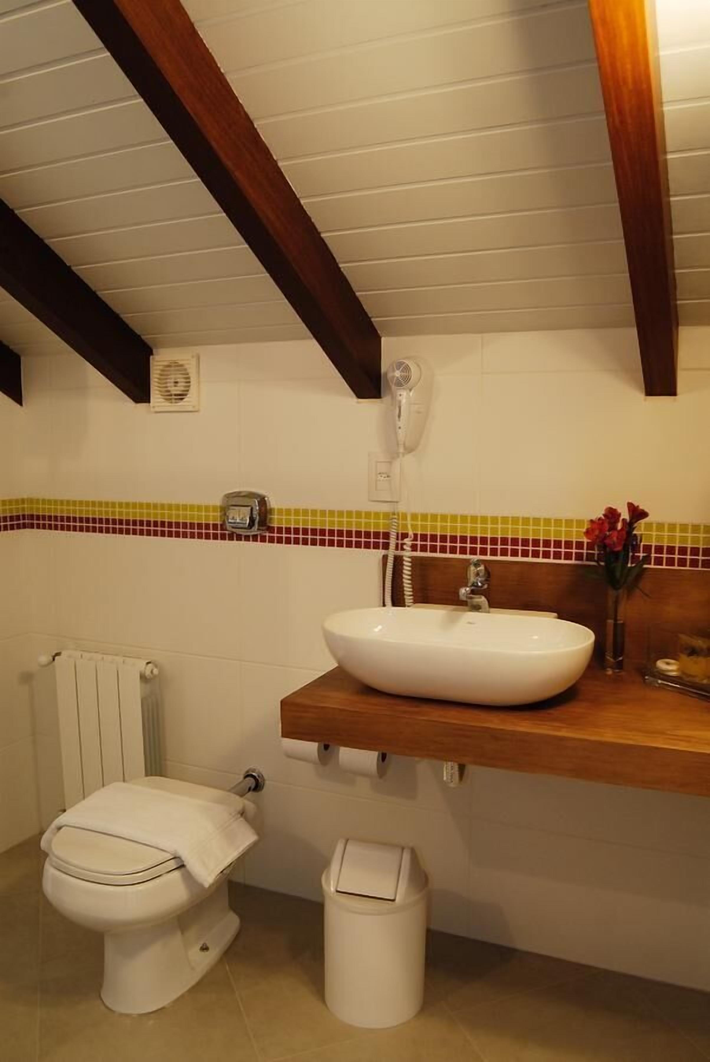 A bathroom with a white sink, wooden countertop, and a tiled backsplash.