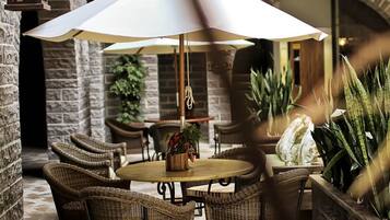 An outdoor patio with wicker furniture, a round table, and a large umbrella.