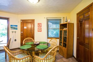 A dining area with a round table, wicker chairs, and a glass cabinet.