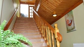 Una escalera de madera con barandilla que lleva a una puerta al final.