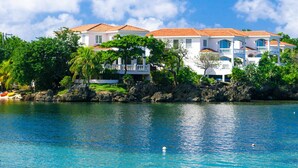 A beachfront property with multiple white buildings, a clear blue sea, and lush greenery. - Coral Vista 1 (Roatan)