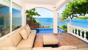 A balcony with a beige sofa, a small table, and a view of the sea. - Coral Vista 1 2 bedroom option (Roatan)