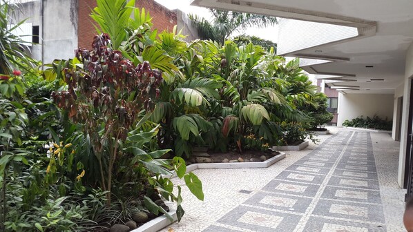 A covered walkway with potted plants and a tiled floor.