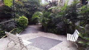 Un sentier dallé, agrémenté de bancs et d’une végétation luxuriante.