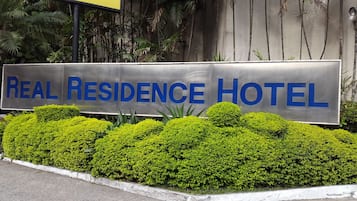 A sign for the Real Residence Hotel with a clear view of the hotel's name.