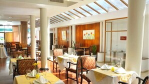 Un restaurant amb diverses taules, caires i un gran finestral amb vistes.
