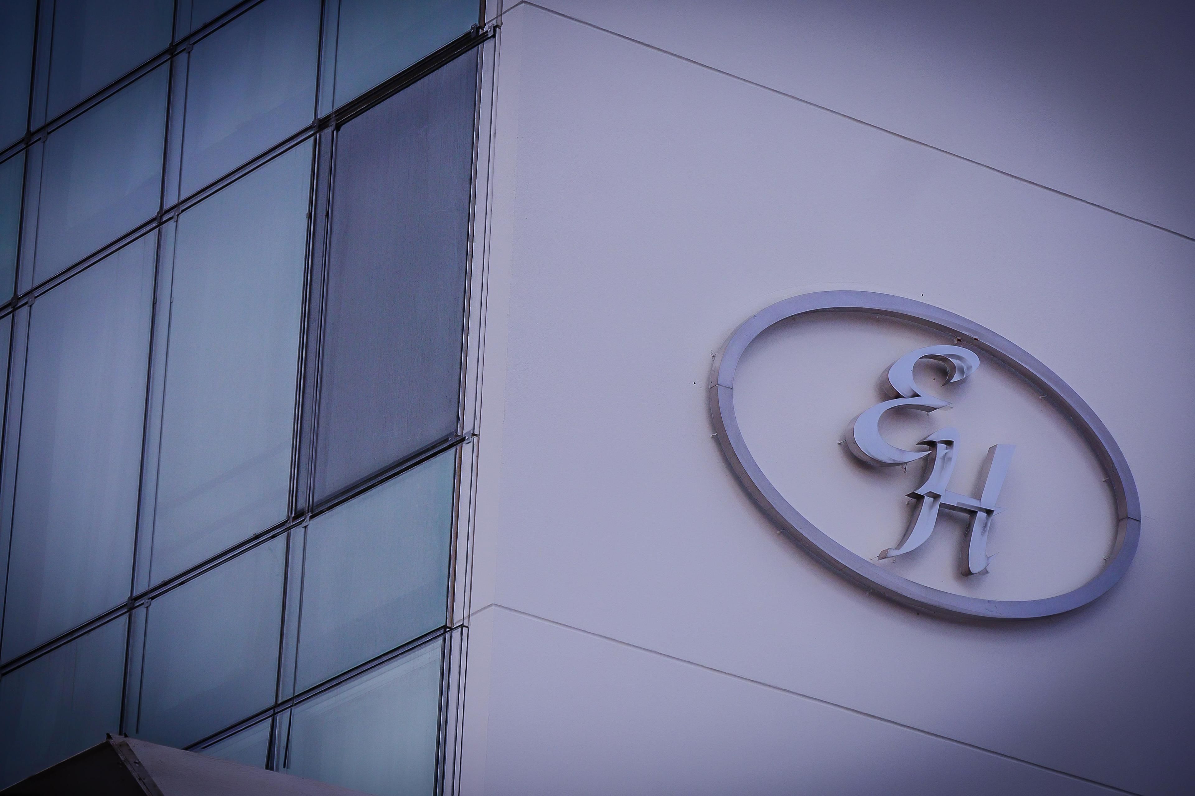 A building with a modern glass facade and a circular logo on the wall.