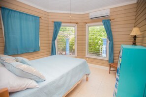A bedroom with a bed, curtains, a window, and a dresser. - Sand Dollar (Roatan)