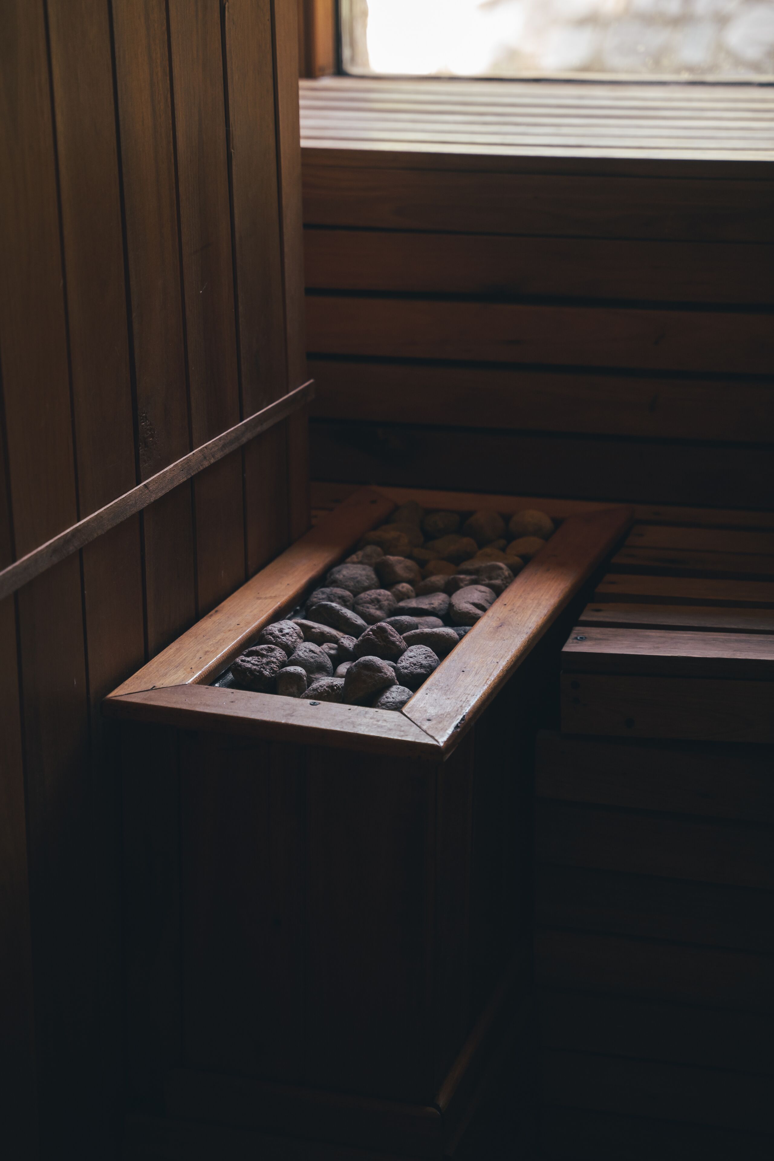 A wooden bench with a built-in planter filled with rocks.