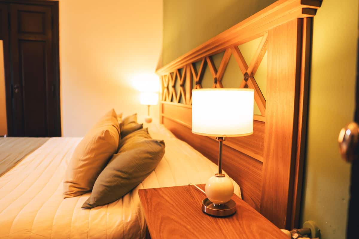 A neatly made bed with pillows, a bedside table, and a lamp.
