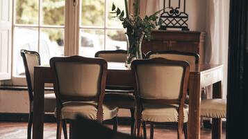 A dining area with a wooden table and chairs, a vase with flowers, and a lamp.