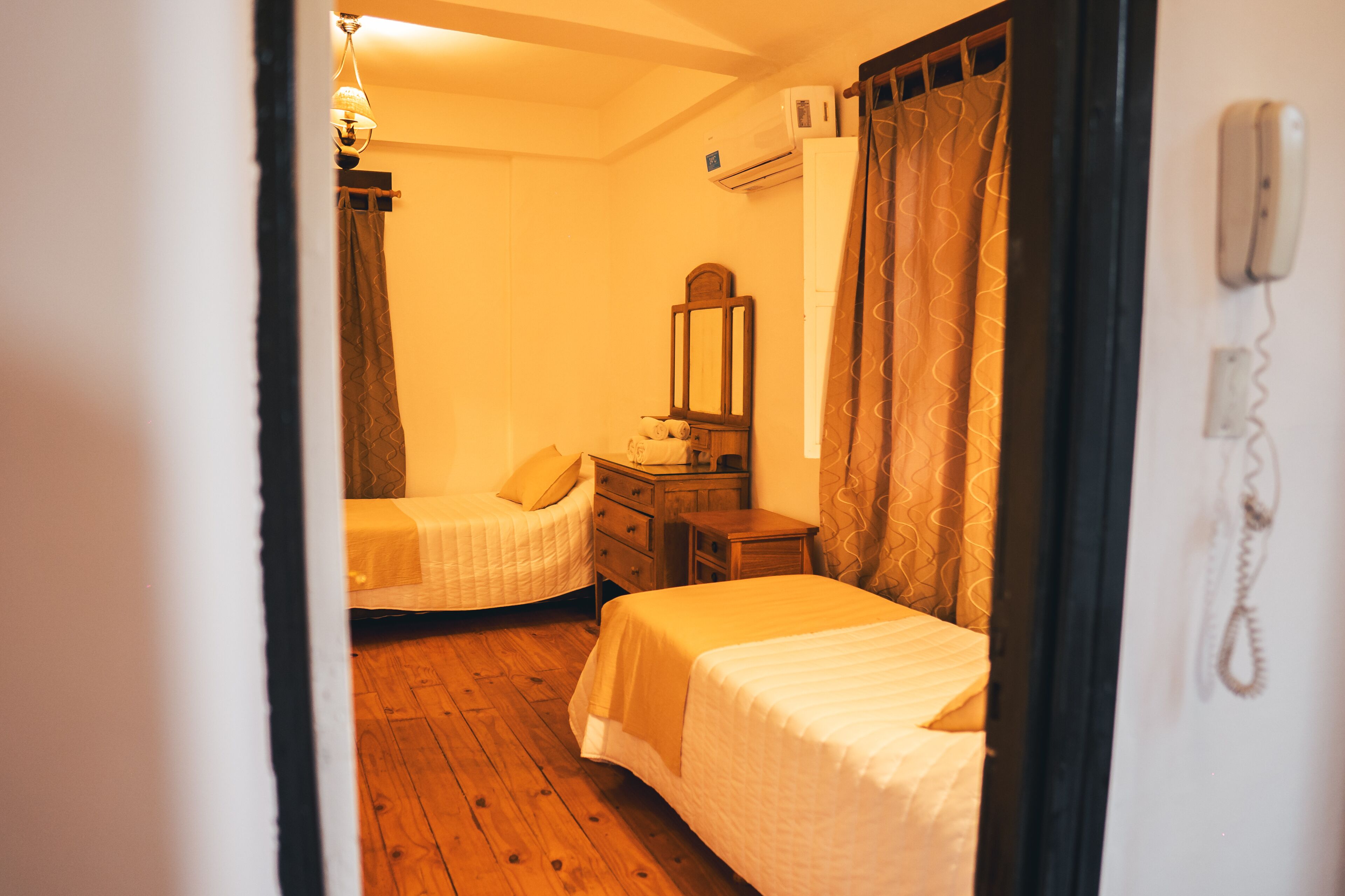 Un dormitorio con dos camas, un aparador, un espejo y un teléfono.