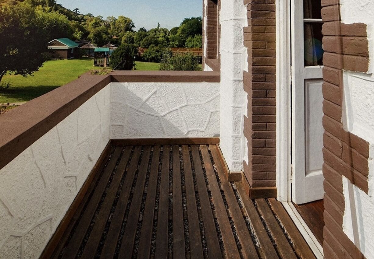 A balcony with a wooden floor and white textured walls.