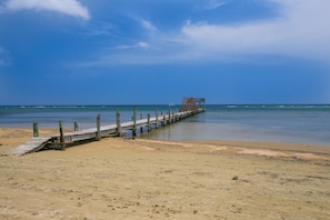 A wooden pier extending into calm waters with a clear sky. - Spooky Channel Villa (Roatan)