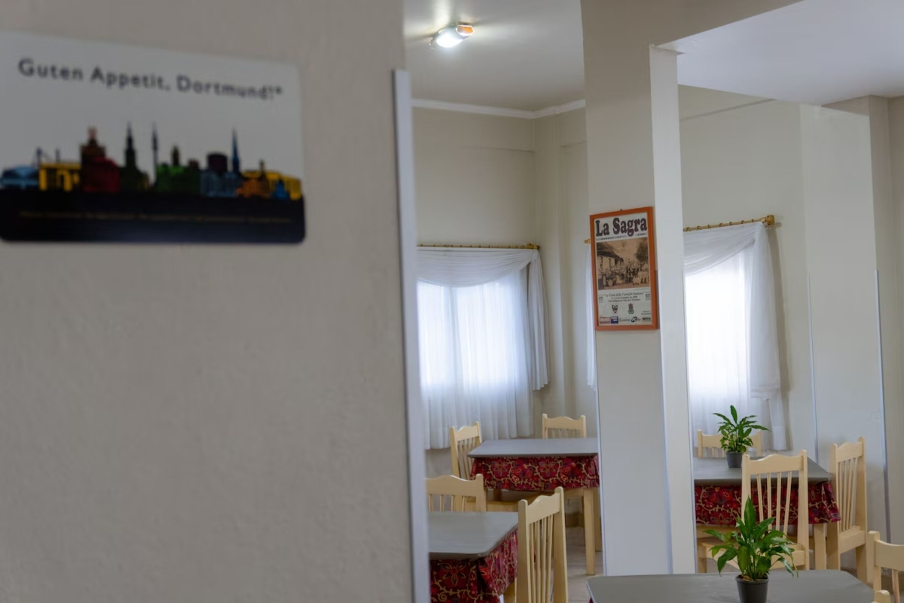 Uma área de refeições com mesas e cadeiras, um cartaz de paisagem urbana e uma placa com a inscrição "La Sagra".